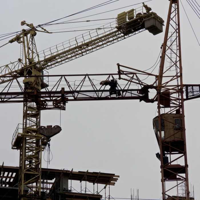 From below of metal industrial cranes located in contemporary construction site against gray sky