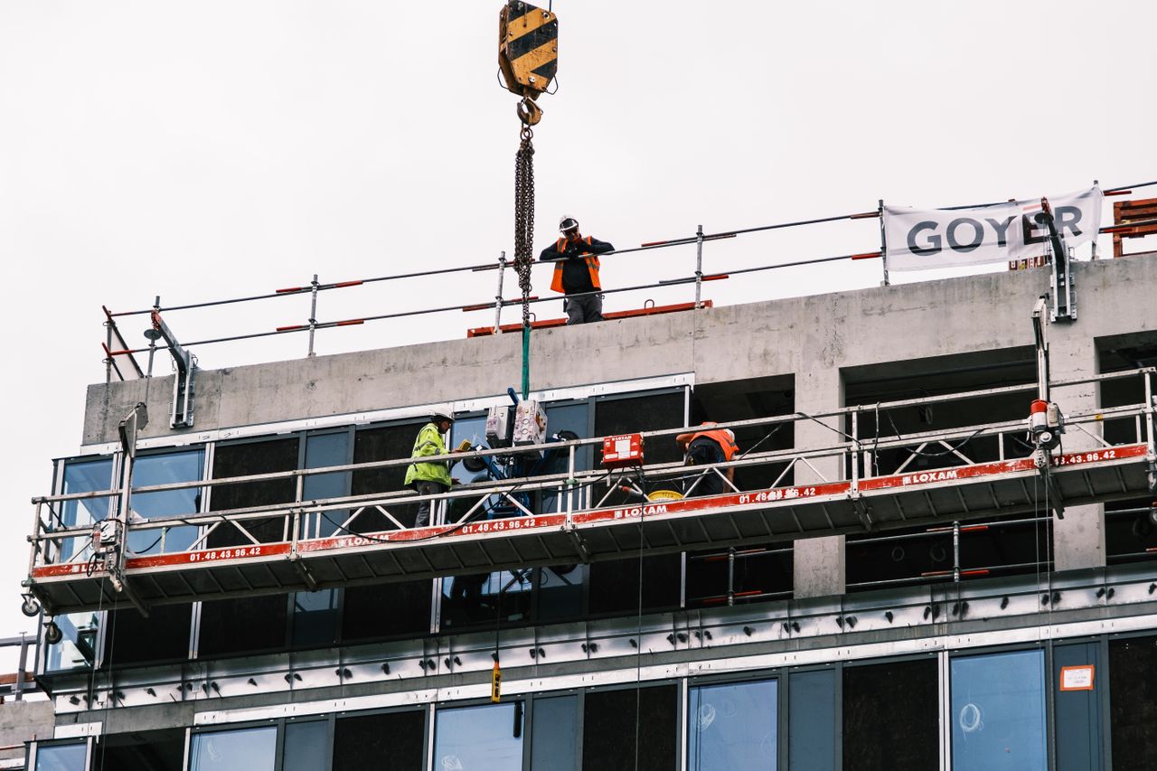 Professional workers at a construction site managing equipment on a high-rise building.